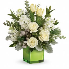 White floral arrangement in a green square vase with roses and tulips