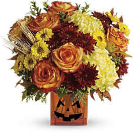 Orange roses and yellow chrysanthemums in a jack-o'-lantern vase