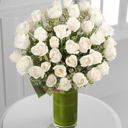 White roses arranged in a green glass vase