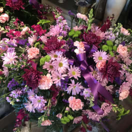 Large pink and purple floral arrangement with a purple ribbon