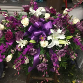 Large purple and white floral spray with a satin ribbon bow