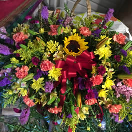Large mixed flower spray with a red ribbon and sunflower center