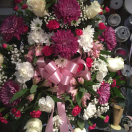 Large bouquet of pink, white, and cream flowers with a pink ribbon