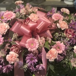 Pink and purple mixed flower arrangement with a large pink bow