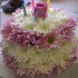 Round bouquet of pink and white daisies with a purple rose and birthday candles