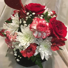 Red roses and white daisies in a black vase with a glitter heart pick