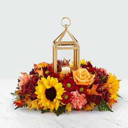 Autumn floral arrangement with sunflowers, roses, and a lantern centerpiece