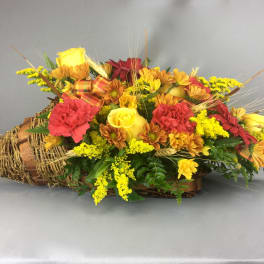 Basket arrangement with yellow roses, red carnations, and daisies