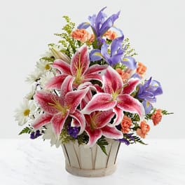 Bouquet of pink lilies, purple irises, and white daisies in a basket