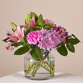 Pink and purple flowers arranged in a clear glass vase