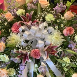 Mixed bouquet with roses, lilies, and a white ribbon bow
