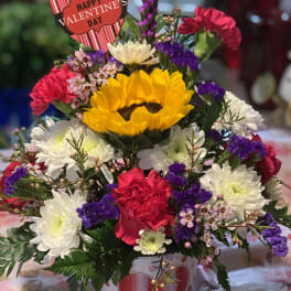 Mixed flower arrangement in a heart-decorated pot with a Valentine sign