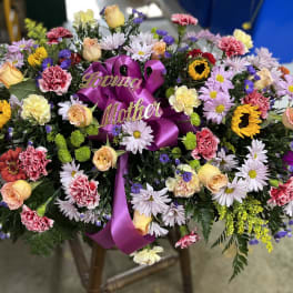 Large floral spray with a purple ribbon and "Loving Mother" sign