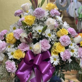 Bouquet of yellow and white roses with pink carnations and daisies in a vase