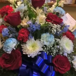 Mixed bouquet with red roses, blue hydrangeas, white lilies, and a blue ribbon