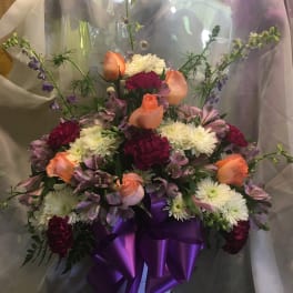 Bouquet of peach roses, white mums, and purple flowers in a white vase