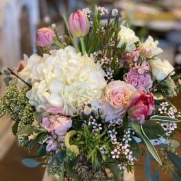 Bouquet of white hydrangeas, pink roses, and tulips in a glass vase