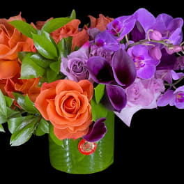 Orange roses and purple orchids in a green vase