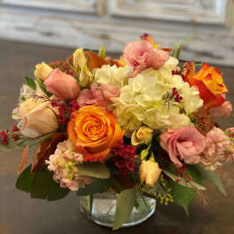 Mixed bouquet of roses, hydrangeas, and pink blooms in a glass vase