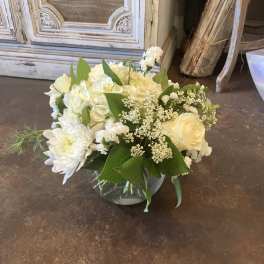 White floral bouquet in a glass vase with roses, hydrangea, and daisies