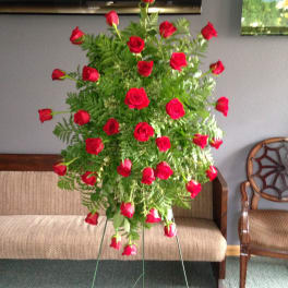 Tall standing arrangement of red roses and greenery on a metal easel