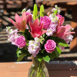 Pink roses and lilies arranged in a clear glass vase