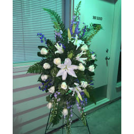 Tall standing floral spray with white lilies and purple flowers on an easel