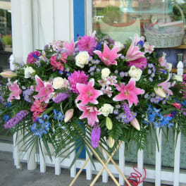 Large standing spray of pink lilies, white roses, and purple flowers