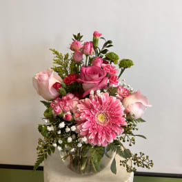 Pink roses and a gerbera daisy in a glass vase
