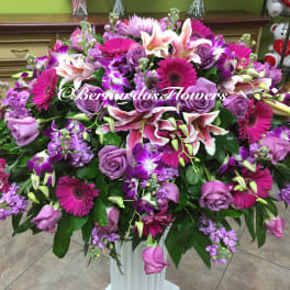 Large bouquet of purple and pink flowers in a white pedestal vase