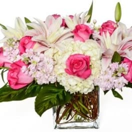 Pink roses and white lilies arranged in a clear glass vase