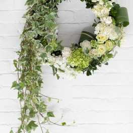 Circular floral wreath with white and green flowers and trailing ivy