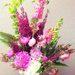 Pink and white floral arrangement in a glass vase with tall green spikes