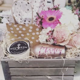 Gift basket with pink flowers, a candle, and a tumbler
