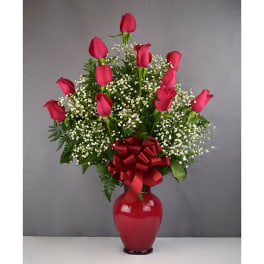 Pink roses in a red vase with baby's breath and a red bow