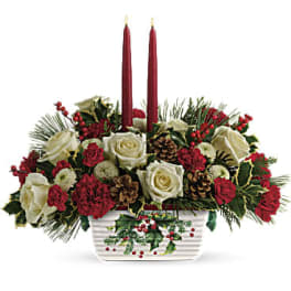 Holiday centerpiece with red and white roses in a white container and two red candles