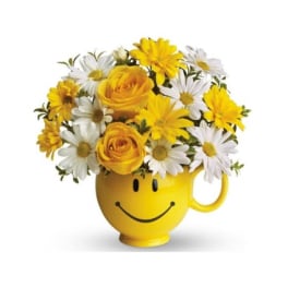 Yellow smiley-face mug filled with yellow roses and white daisies