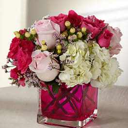 Pink and white roses with hydrangeas in a magenta glass vase