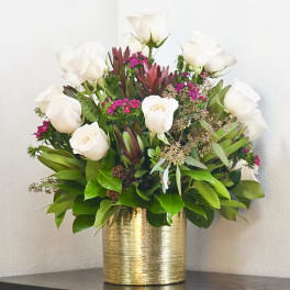 White roses and pink flowers arranged in a gold vase