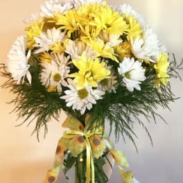 Yellow and white daisy bouquet in a glass vase with a ribbon