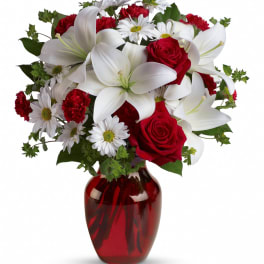 Red roses and white lilies in a red glass vase