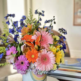 Colorful mixed bouquet in a pastel vase with a butterfly decoration