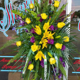 Tall standing floral spray with yellow roses and lilies, accented by purple flowers