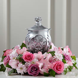 Pink floral arrangement surrounding a silver urn