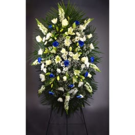 Tall funeral spray of white and blue flowers on a stand