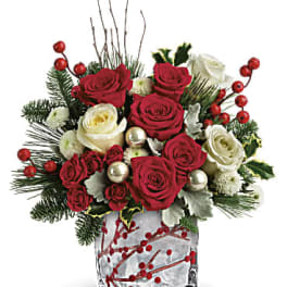 Red and white roses arranged in a clear glass vase with berries