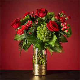 Red roses and carnations in a clear glass vase with green filler
