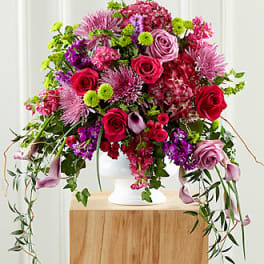 Large pink and purple floral arrangement in a white vase