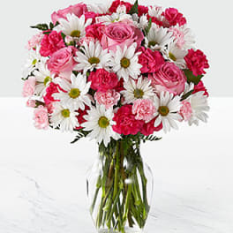 Pink roses and white daisies arranged in a clear glass vase