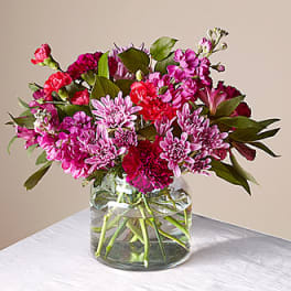 Pink and magenta flowers arranged in a clear glass vase
